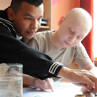 Navy seaman draws pictures with a child at a children's cancer ward